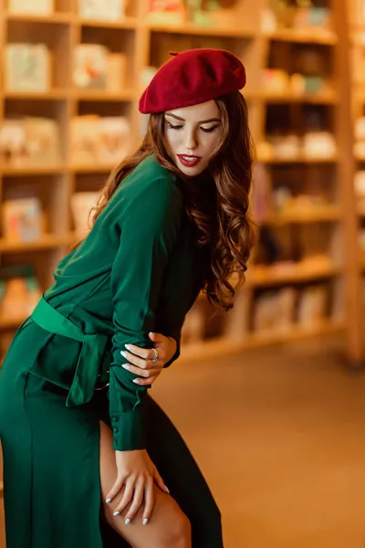 Jeune femme européenne dans une librairie, une dame brillamment habillée dans un béret avec un livre — Photo