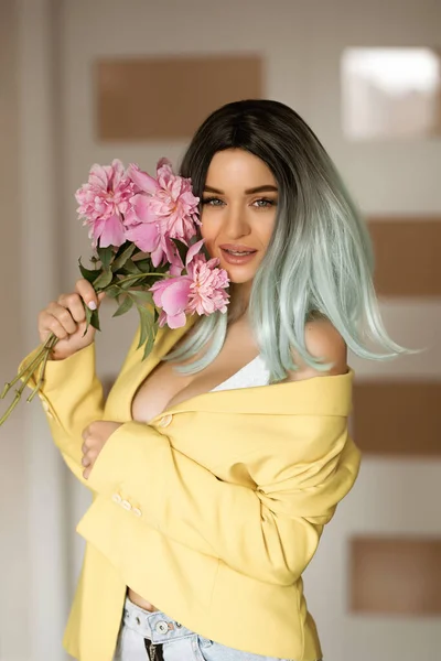 En ung kaukasisk kvinna i en blå peruk, en dam med ljust hår och blommor, en fashionabel ljus kvinna — Stockfoto