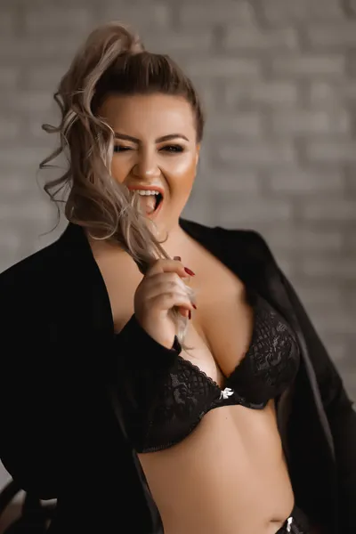 Plus-size woman with long blond hair in lingerie , overweight blonde with lush forms in the loft, full girl in black clothes with bright makeup — Stock Photo, Image