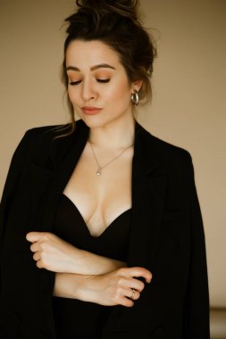 Siyah ceketli güzel beyaz bir kadının portresi, ince, saç stili ve makyajlı seksi bir kadın, bej arka planda bir iş elbisesi içinde şık, ciddi bir esmer..