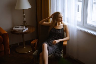 Sarışın, uzun saçlı, beyaz bir kadın pencerenin kenarındaki sandalyede, kara kara kara düşünen güzel bir kadın, tavan arasında bir sarışının portresi...