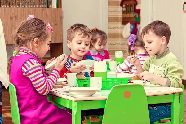 Mädchen und Jungen essen am Tisch — Stockfoto