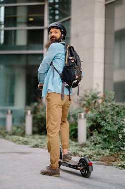 Genç adam şehirde scooter kullanıyor.