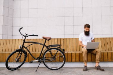 Young man having a short break from a bike ride sitting on the bench