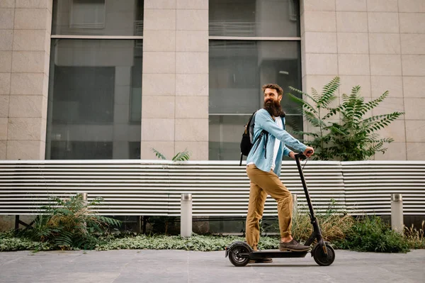 Young hipster man driving electric scooter after work. Ecological transportation concept.