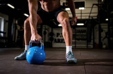 Spor giyim sektöründe formda genç bir adam spor salonunda bir halteri kaldırmaya odaklanmıştı.