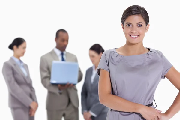 Woman with hands on her hips with business team in the backgroun — Stock Photo, Image