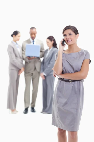 Businesswoman looking up on the phone with co-workers in the bac — Stock Photo, Image