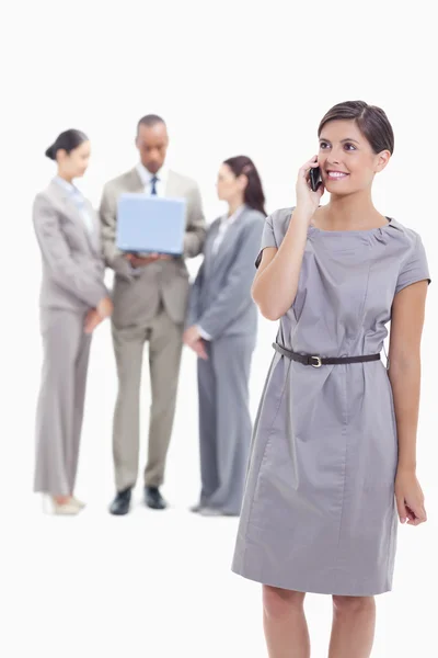 Businesswoman smiling on the phone with one arm along her body a — Stock Photo, Image