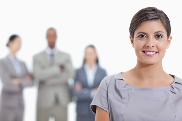 Gran primer plano de una mujer de negocios sonriendo y un equipo en segundo plano —  Fotos de Stock