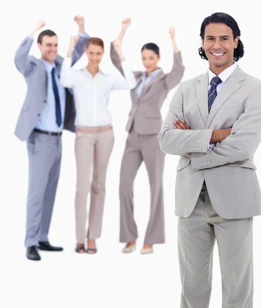 Empresario sonriendo y cruzando los brazos con gente entusiasta — Foto de Stock