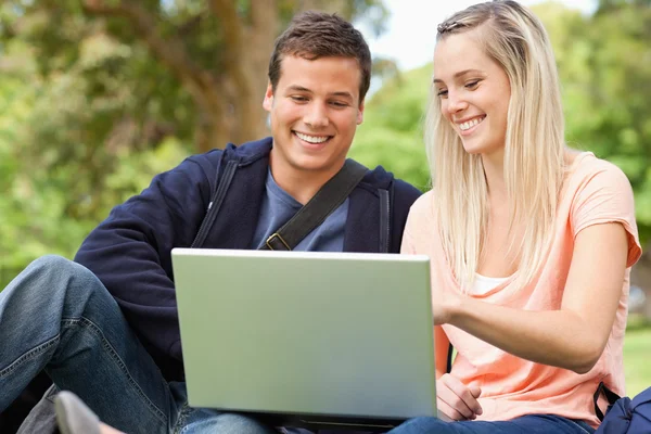 Jovem sentado enquanto usa um laptop — Fotografia de Stock