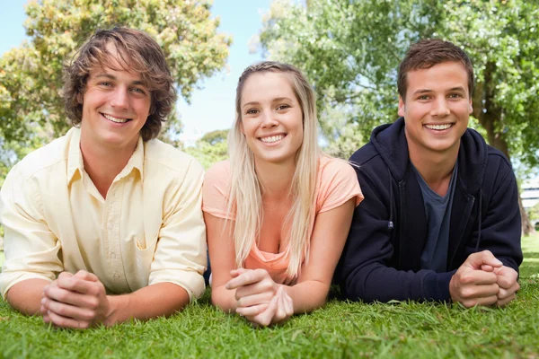 Porträtt av tre leende studenter i en park — Stockfoto