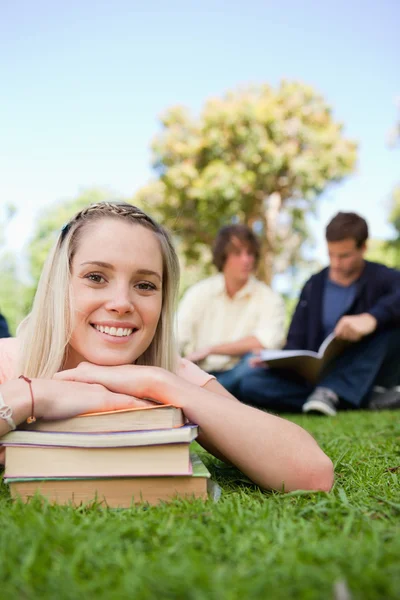 Close-up van een meisje liggend hoofd op haar boeken in een park — Stockfoto