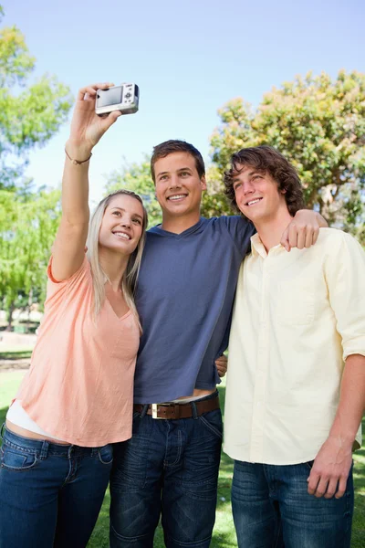 Tres amigos sonrientes sacándose fotos — Foto de Stock