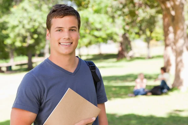 Porträtt av en student leende medan du håller en lärobok — Stockfoto