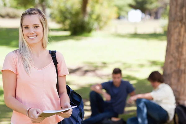 Porträtt av en kvinnlig student leende medan du håller en lärobok — Stockfoto