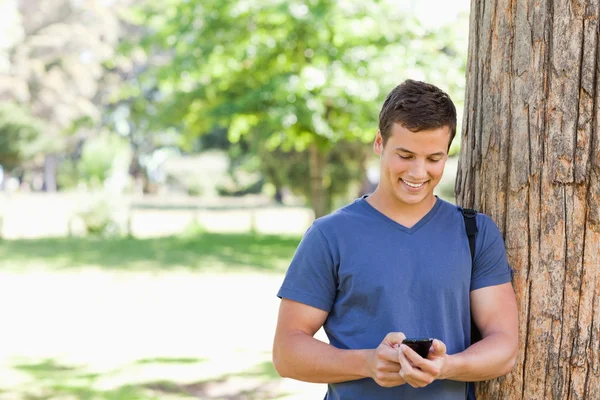Muscled student using a smartphone — Stock Photo, Image