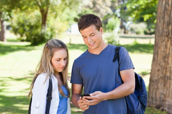 Close-up of a student showing his smartphone to a girl — Stock Photo, Image