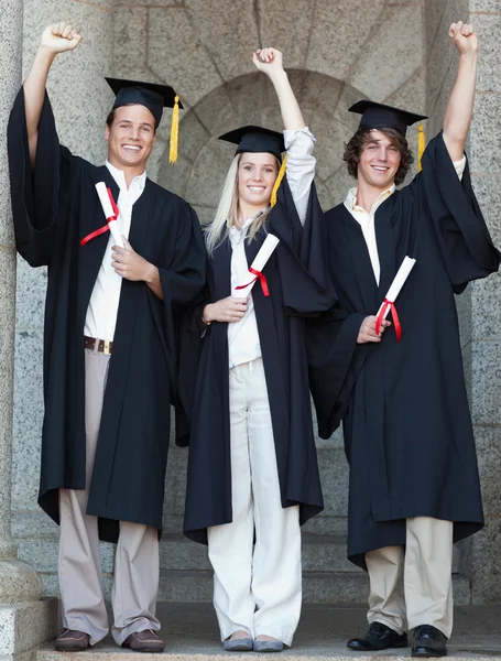 Sorrindo graduados levantar braço — Fotografia de Stock