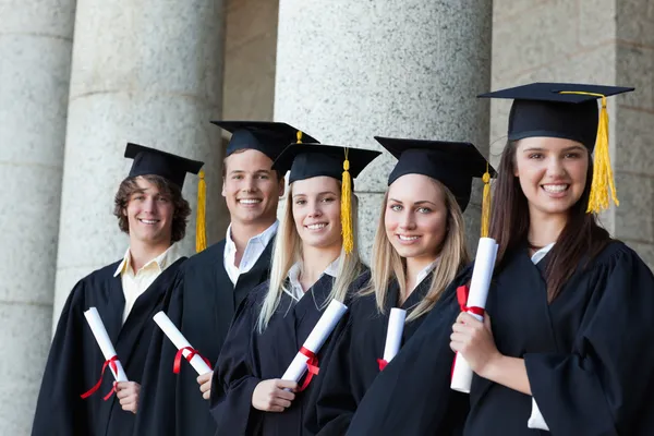 Graduados sonrientes posando en una sola línea — Foto de Stock