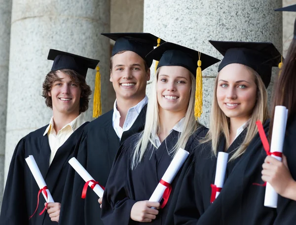 Porträtt av leende utexaminerade poserar i rad — Stockfoto