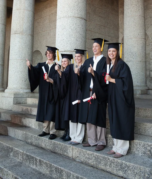 Graduados riendo posando el pulgar hacia arriba — Foto de Stock