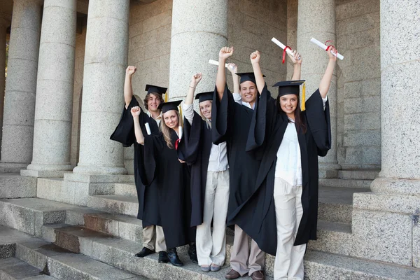 Fem glada studenter poserar de höjde armarna — Stockfoto