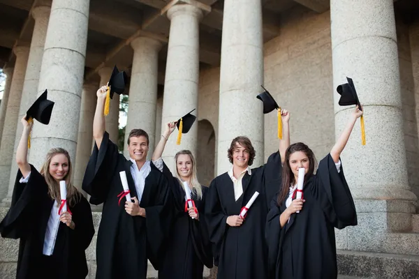 Graduados segurando seus chapéus — Fotografia de Stock