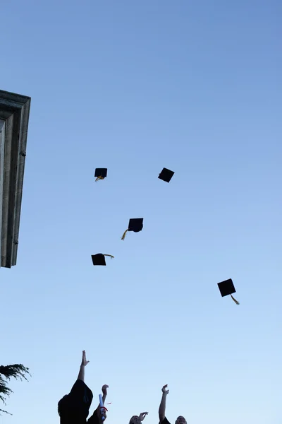 Estudiantes de grado lanzando sus sombreros al cielo — Foto de Stock