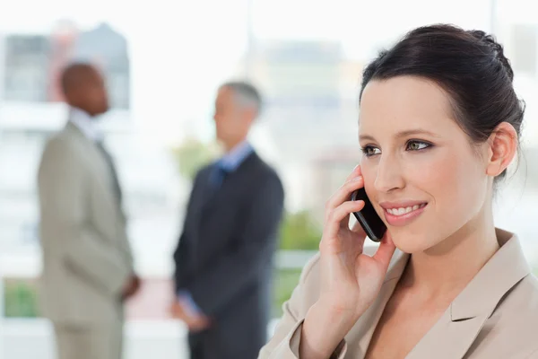 Junge Sekretärin telefoniert, während sie lächelt und nach — Stockfoto