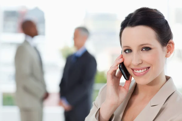 Secretary talking on the phone while looking at the camera — Stock Photo, Image