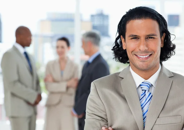 Young smiling executive looking at the camera in front of his te — Stock Photo, Image