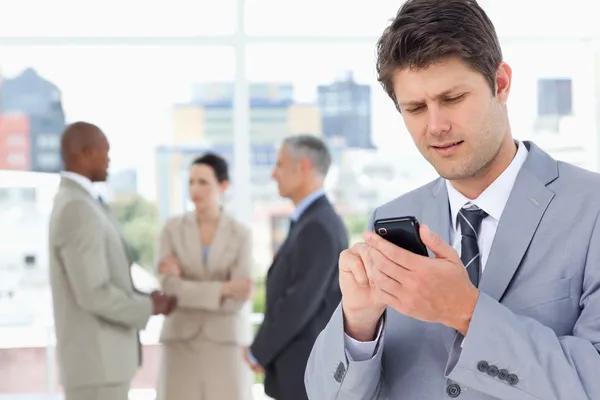 Junger Manager, der mit seinem Mobiltelefon in einem Konzentrat eine SMS verschickt — Stockfoto