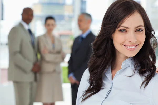 Giovane donna esecutiva sorridente e guardando avanti con il team in — Foto Stock