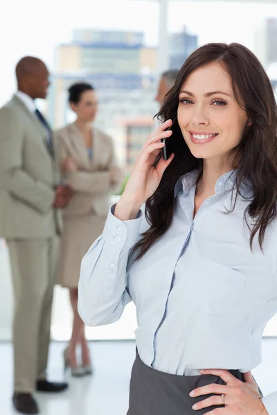 Femme d'affaires souriante parlant au téléphone avec une main sur elle — Photo