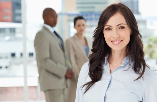 Молодая улыбающаяся деловая женщина, стоящая перед своими коллегами — стоковое фото