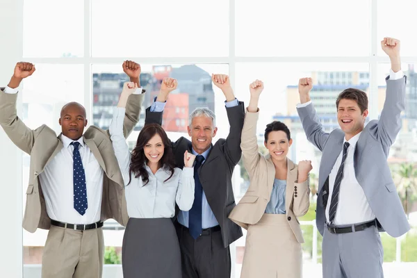 Sonriente equipo de negocios de pie con los brazos levantados en suceso — Foto de Stock