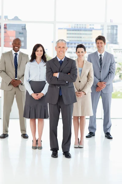 Smiling mature director crossing his arms in front of his team — Stock Photo, Image