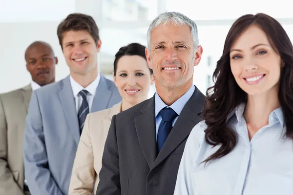 Cuatro empleados sonrientes de pie alrededor de su director — Foto de Stock