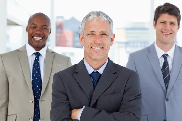 Mature director standing upright in front of his two smiling exe — Stock Photo, Image