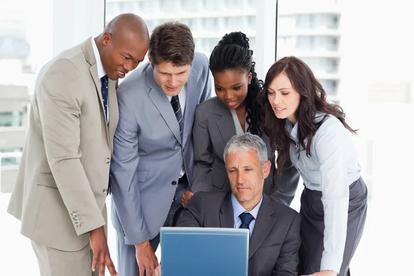 Mogna manager ger förklaringar till sitt team med en bärbar dator — Stockfoto