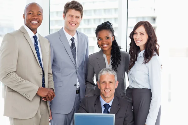 Mature manager smiling with a computer among his team — Stock Photo, Image