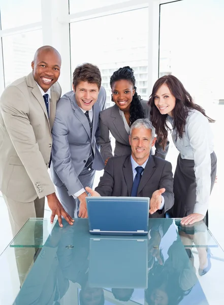 Four business standing behind their manager proudly showi — Stock Photo, Image