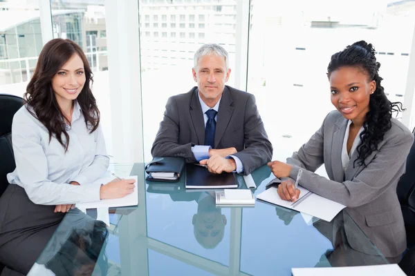 Mature director sitting at the desk and accompanied by two busin — Stock Photo, Image