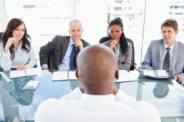 Vier Geschäftsleute sitzen am Schreibtisch und hören aufmerksam zu. — Stockfoto