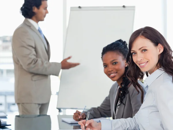 Two young smiling employees working while listening to a present — Stock Photo, Image