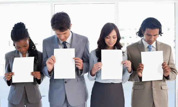 Young business team showing blank sheets while bowing their head — Stock Photo, Image