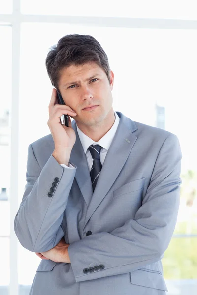 Homem de negócios sério fazendo uma chamada enquanto olha para a câmera — Fotografia de Stock