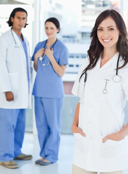 Glimlachend vrouwelijke arts permanent rechtop met haar handen in haar poc — Stockfoto